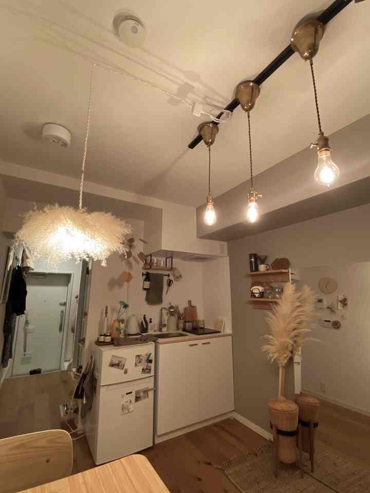 Natural modern kitchen space with white walls and gold Edison bulbs, featuring rattan decor and warm natural tones