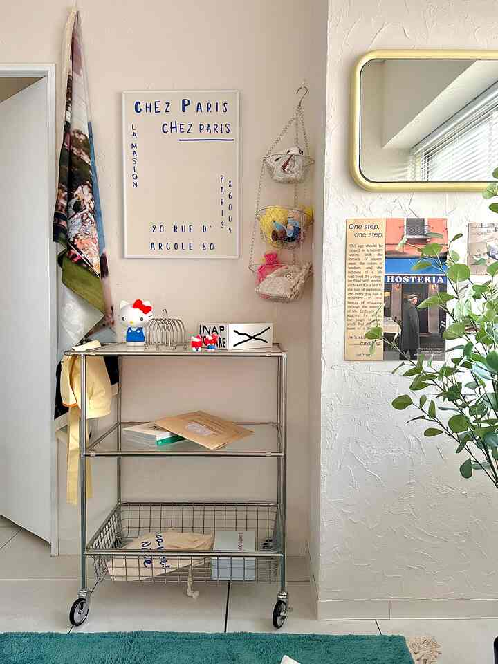 Cozy storage space with white walls and silver 3-tier trolley, beige textured wall and yellow framed mirror as accent elements
