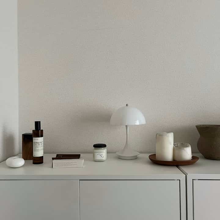 白色調でシンプルなナチュラルな棚の空間、キャンドルとテーブルランプが配置されたすっきりとしたインテリア