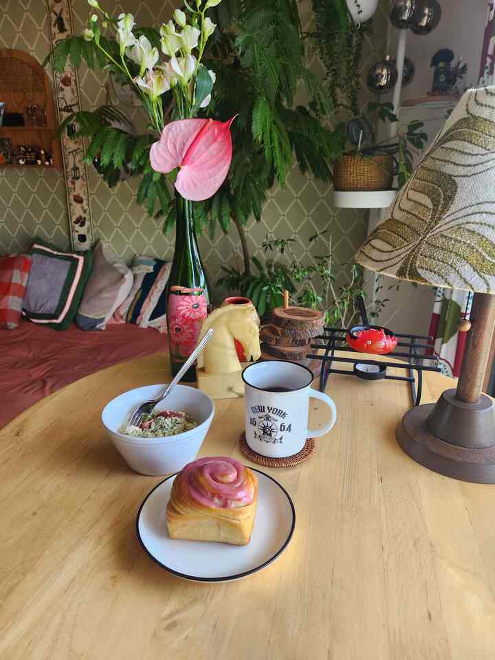 ナチュラルなブラウン色調のリビング、木製のテーブルにコーヒーとペストリーが置かれた、雰囲気のあるホームカフェ空間