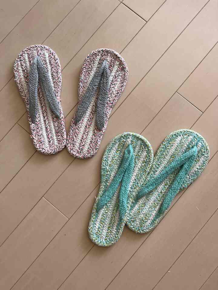 淡い茶色の床に置かれたカラフルな夏用コットンスリッパ2足の写真