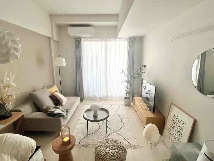 Soft beige natural tone living room featuring gray sofa, round coffee table, floor lamp, and plant creating a cozy atmosphere