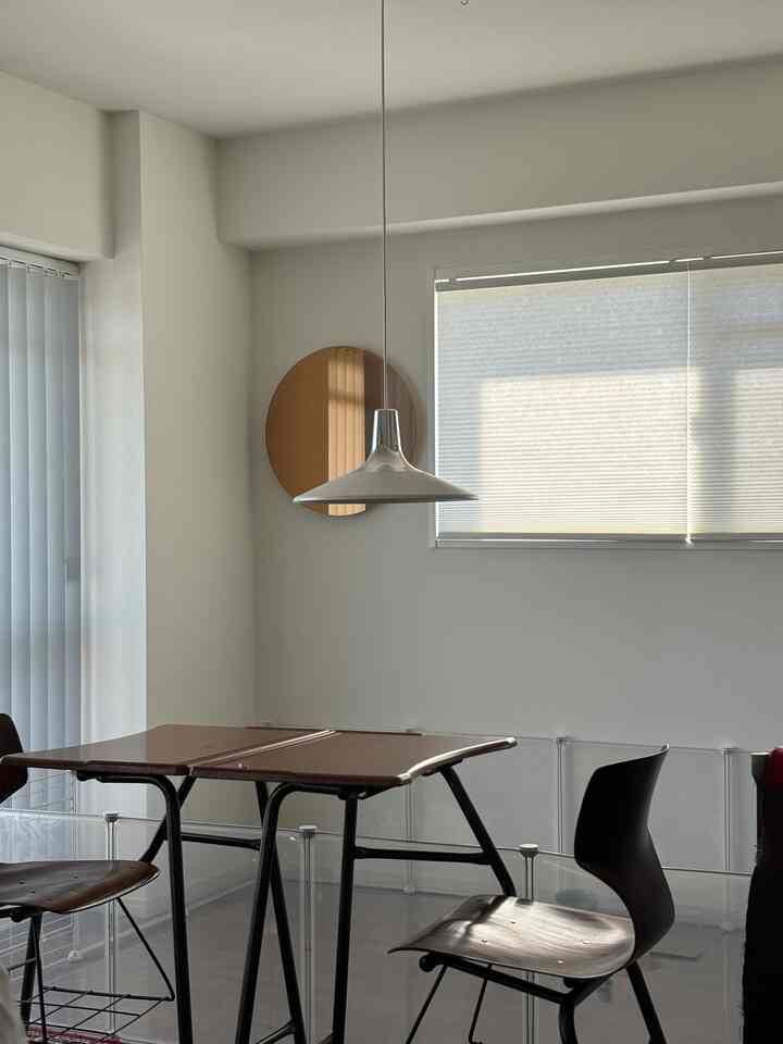 白とブラウンのトーンのダイニング、透明なペットゲートとシンプルな家具が配置された落ち着いた雰囲気の空間