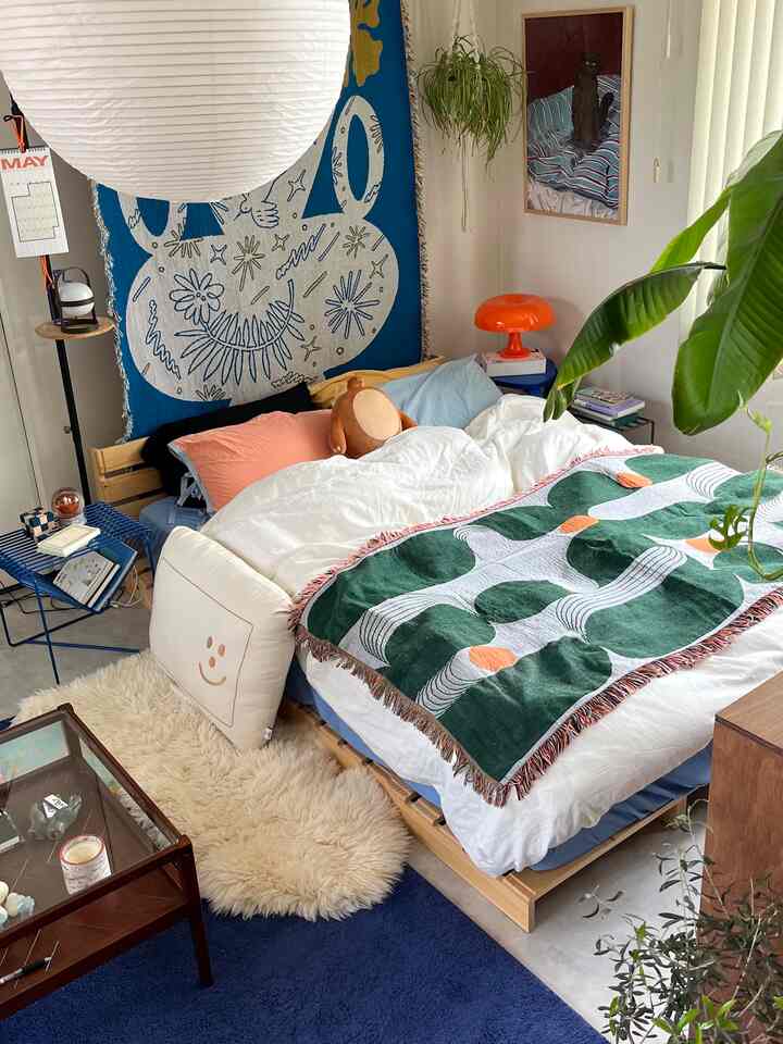 ブルーとナチュラルウッドトーンの寝室、クッションと植物が調和した雰囲気のある空間