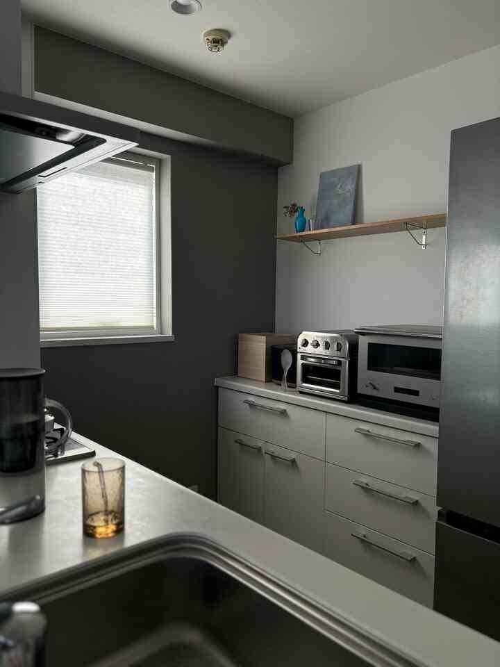 白とグレーのトーンのキッチン、すっきりとした収納とステンレス家電が調和したモダンなインテリア