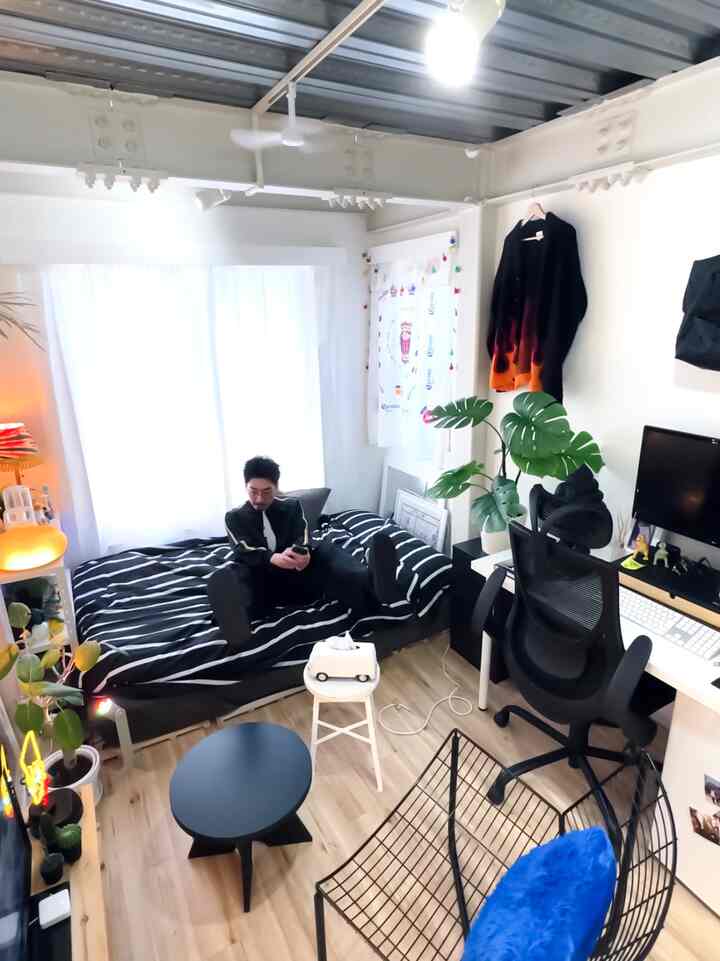 Bright white-toned 6-tatami studio apartment with black furniture, featuring bed, desk, and plants in a cozy single household room