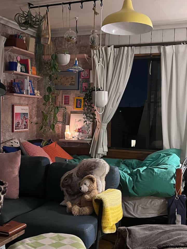 暖かいイエローの照明とナチュラルな色調の、ソファとベッドが配置された居心地の良い寝室のインテリア