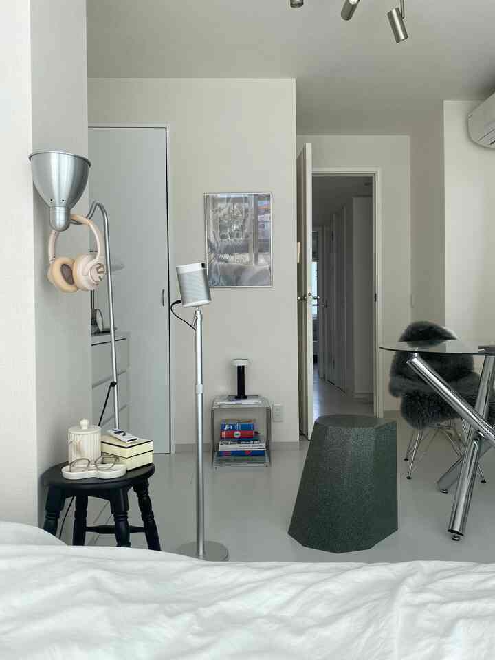 White and silver toned living room featuring stools and a floor lamp with a simple and modern interior design