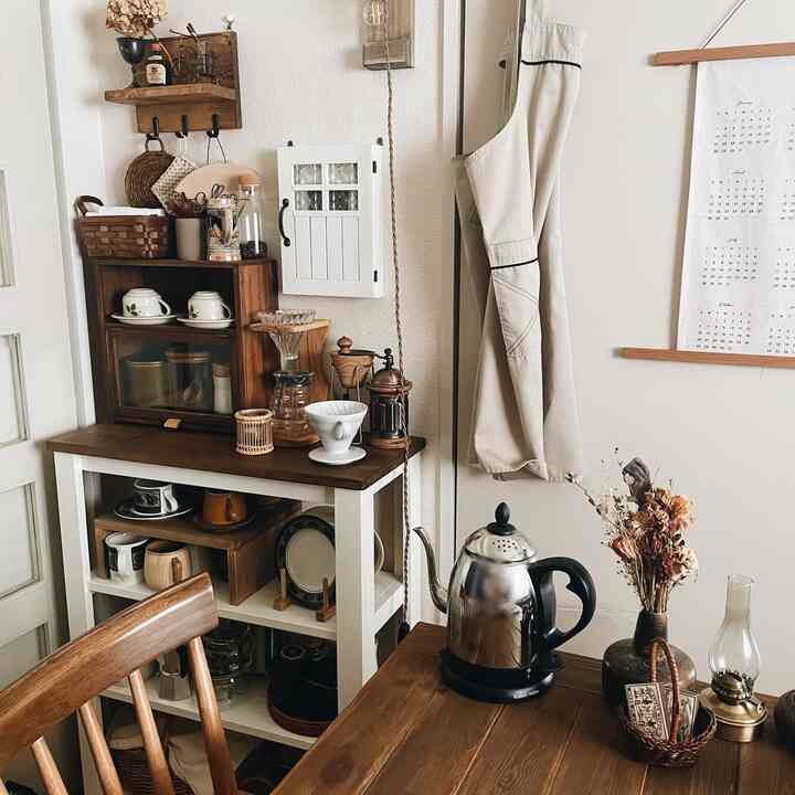 白い壁と木目調の家具が調和するキッチン空間、コーヒー用具とヴィンテージアイテムが配置された雰囲気のあるおうちカフェ