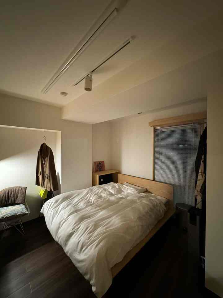 White and brown toned bedroom featuring a wooden bed frame with tidy bedding, creating a cozy atmosphere