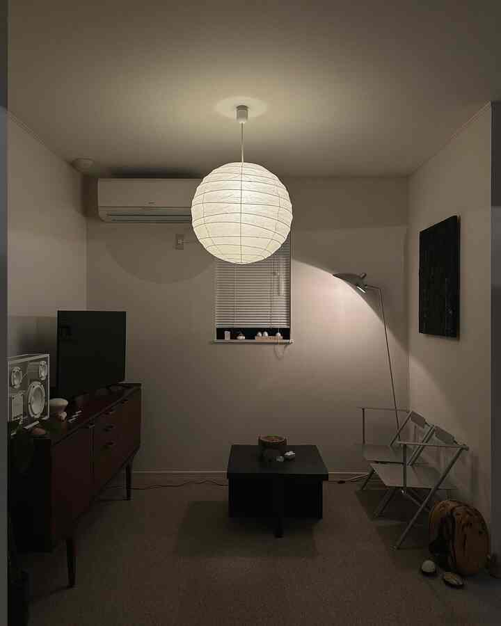 白と黒のトーンのミニマルなリビング、中央にペンダントライトとコーヒーテーブルが配置された落ち着いた空間