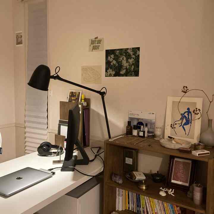 白と木目調の調和が取れたホームオフィスワークスペース、黒いテーブルランプと木製ディスプレイラックがアクセントの整理された空間