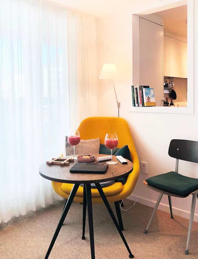 Bright yellow armchair and round side table in a small home cafe style cozy corner