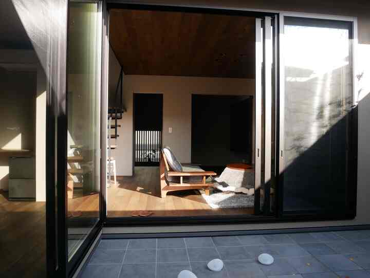 温かみのある木目調のリビング、ソファと引き戸が配置された雰囲気のある空間