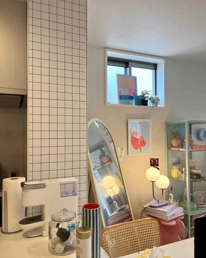 白とグレーのトーンのキッチン空間、モダンなテーブルランプとラタンのダイニングチェアが配置された雰囲気のあるインテリア