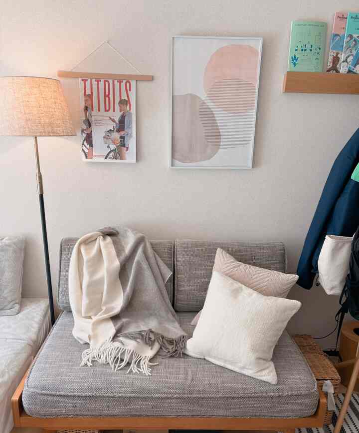 Natural-toned living room featuring a wooden frame sofa with beige blanket and cushions creating a cozy atmosphere