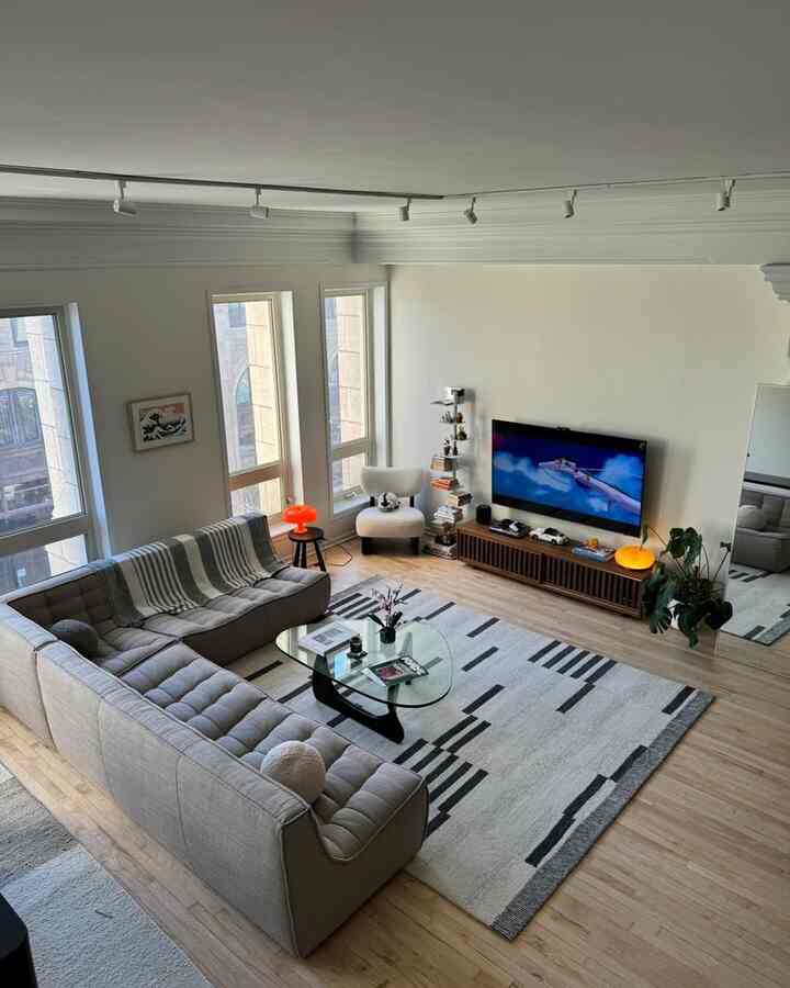 A white and natural-toned living room featuring gray sectional sofa and patterned rug with a modern, spacious atmosphere