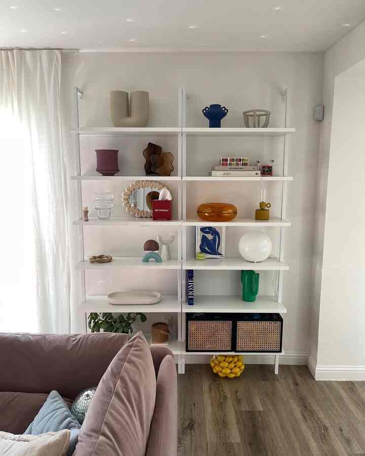 Living room with white walls and shelving, featuring a light purple sofa and natural wood-tone flooring in a modern Nordic style