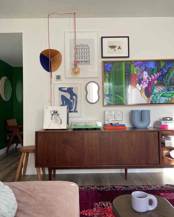 Retro style living room with white walls and a dark brown wooden sideboard, featuring framed wall art and pendant lighting