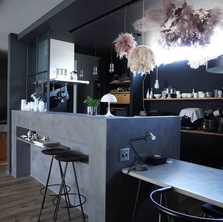 Modern kitchen in gray and black tones, featuring a central counter, pendant lights, and decorative dried flowers for a sophisticated atmosphere