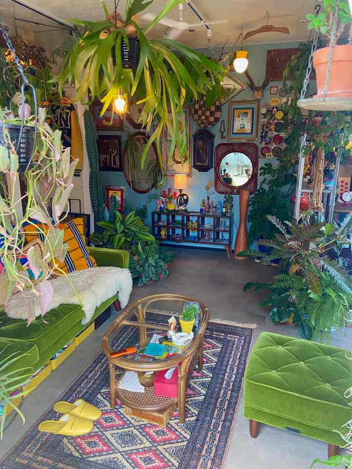 Green-toned living room featuring vintage furniture and abundant houseplants, decorated with retro accents creating a cozy atmosphere