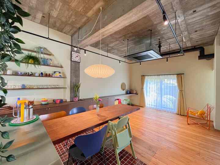 Warm wood tone mid-century modern dining room featuring a long wooden table, bubble pendant light, and colorful dining chairs