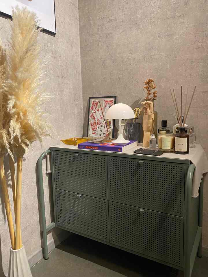 Beige wall nook featuring a gray-green storage cabinet with a white table lamp and diffuser on top, creating a natural and cozy atmosphere