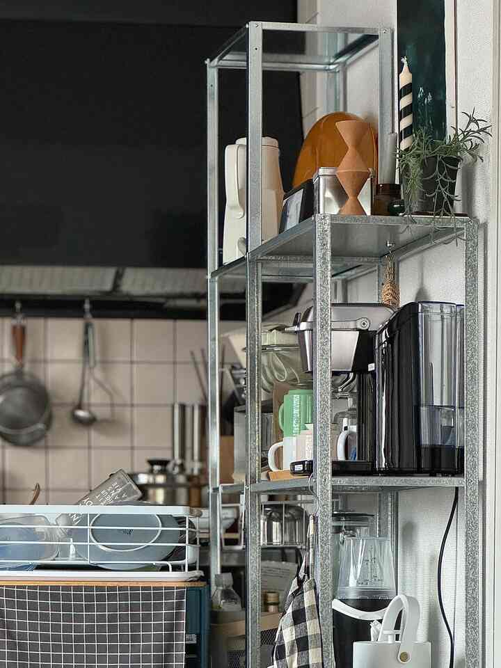 シルバーのメタル棚とコーヒーメーカーが置かれた黒を基調としたキッチン、コンパクトな1LDK一人暮らしの空間