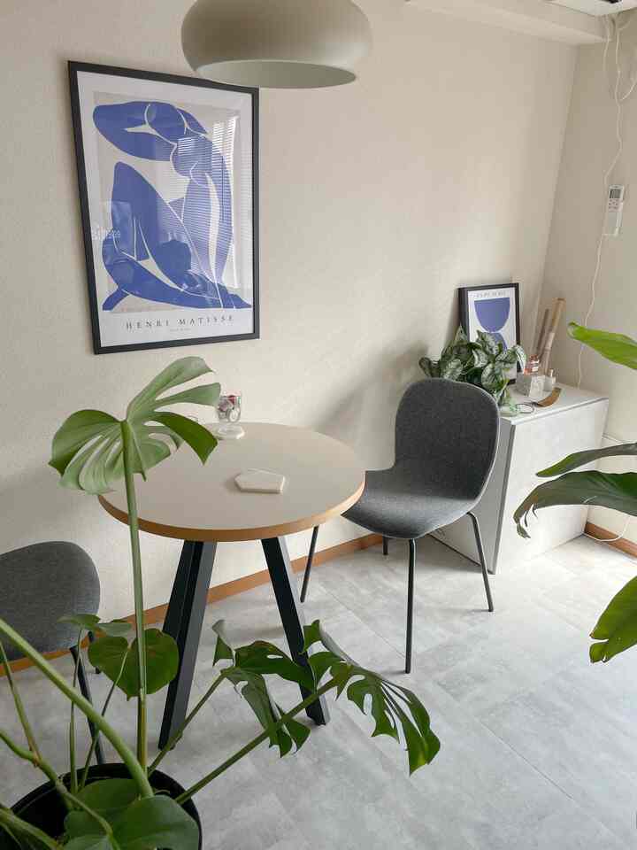 Natural modern small living room featuring a round cafe table with gray dining chairs and lush green plants, with neat ambiance