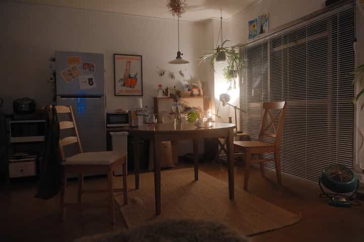 暖かいブラウンとホワイトのトーンのナチュラルなダイニング、ダイニングテーブルと椅子、植物が配置された居心地の良い空間