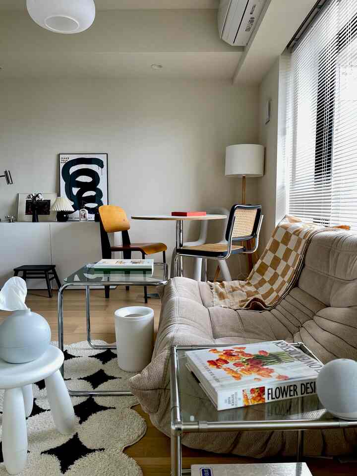 ベージュと白のトーンのリビング、曲線のソファと丸いダイニングテーブル、サイドテーブルが配置されたシンプルでナチュラルなインテリア