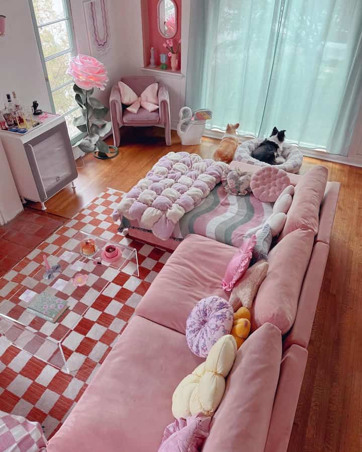 Pink-toned living room featuring a pink sofa, armchair, and two dogs in pet beds, creating a lovely atmosphere