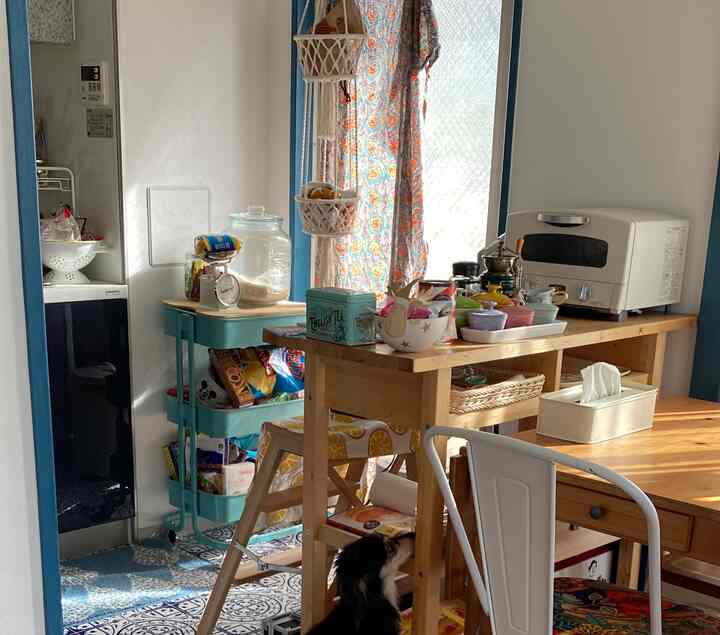 ブルーとナチュラルカラーのキッチン、キッチンワゴンとダイニングテーブルが配置された雰囲気のあるインテリア