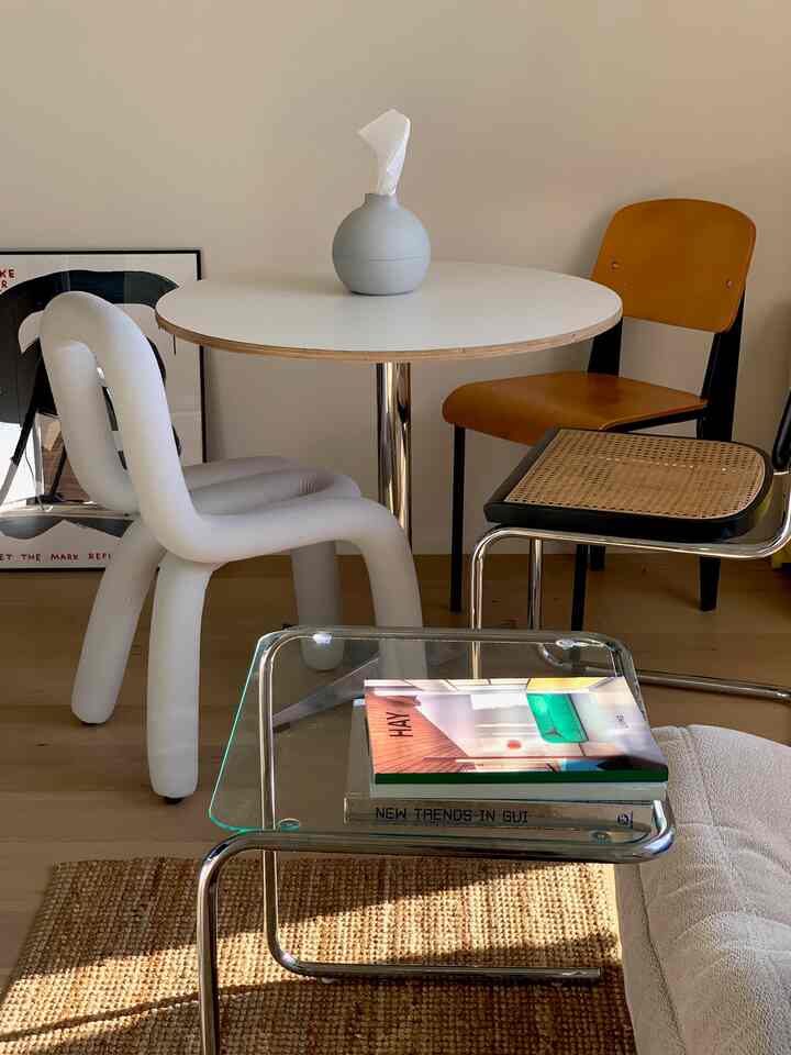 明るいホワイトとウッドトーンの2Kダイニング、透明なガラスのコーヒーテーブルとシンプルなダイニングチェアが配置された清潔感のある空間