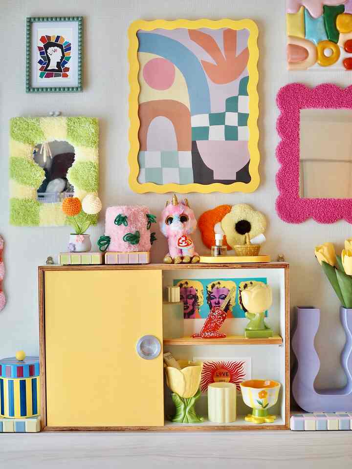 明るい黄色のキャビネットが中央下部に配置された北欧風インテリア、多彩な装飾が印象的な雰囲気を演出