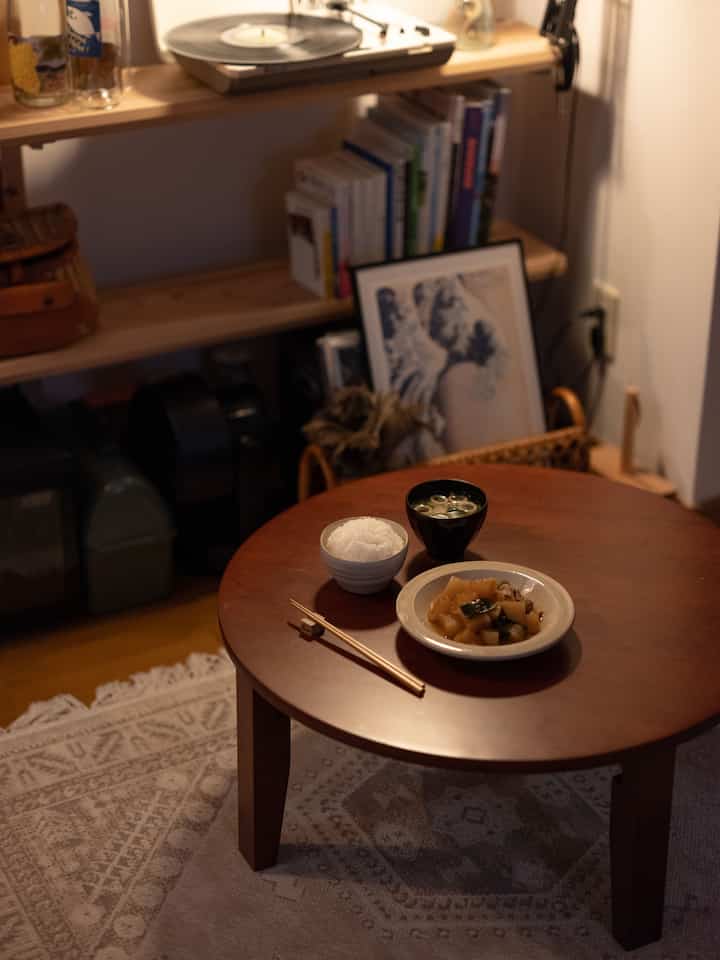Wood tone compact studio dining area featuring a round table set with rice, soup, and side dishes creating a cozy atmosphere