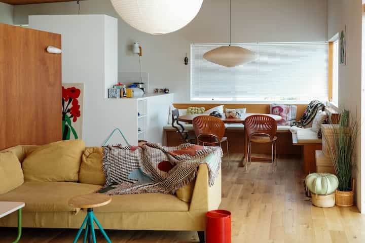 ナチュラルな木目調と黄色のソファが配置された4人暮らし向けのリビング・ダイニング、開放的なレイアウトの空間