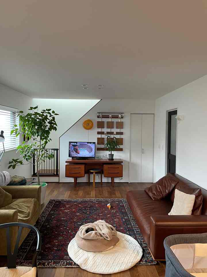 A cozy living room with white walls, brown furniture, natural tones, featuring a pet bed and patterned rug