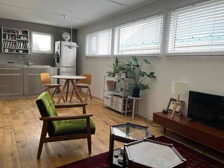 Bright white walls with wood-tone flooring in a living room and kitchen space featuring dining table and vintage armchair for a natural vibe