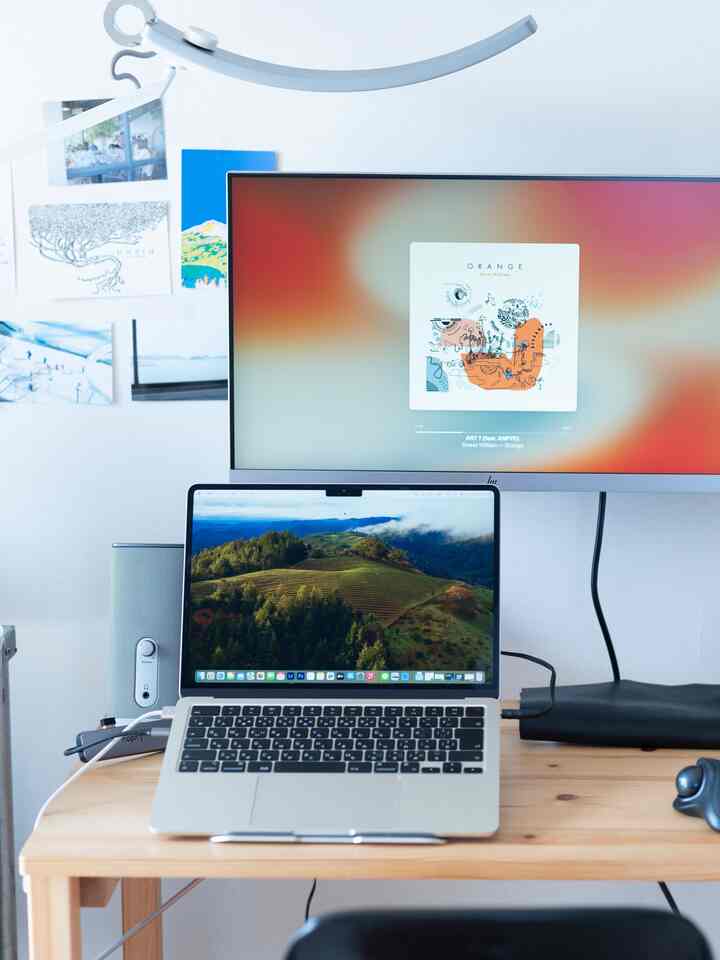 White and wood tone home office space featuring a desk with a laptop and large monitor, creating a clean work environment