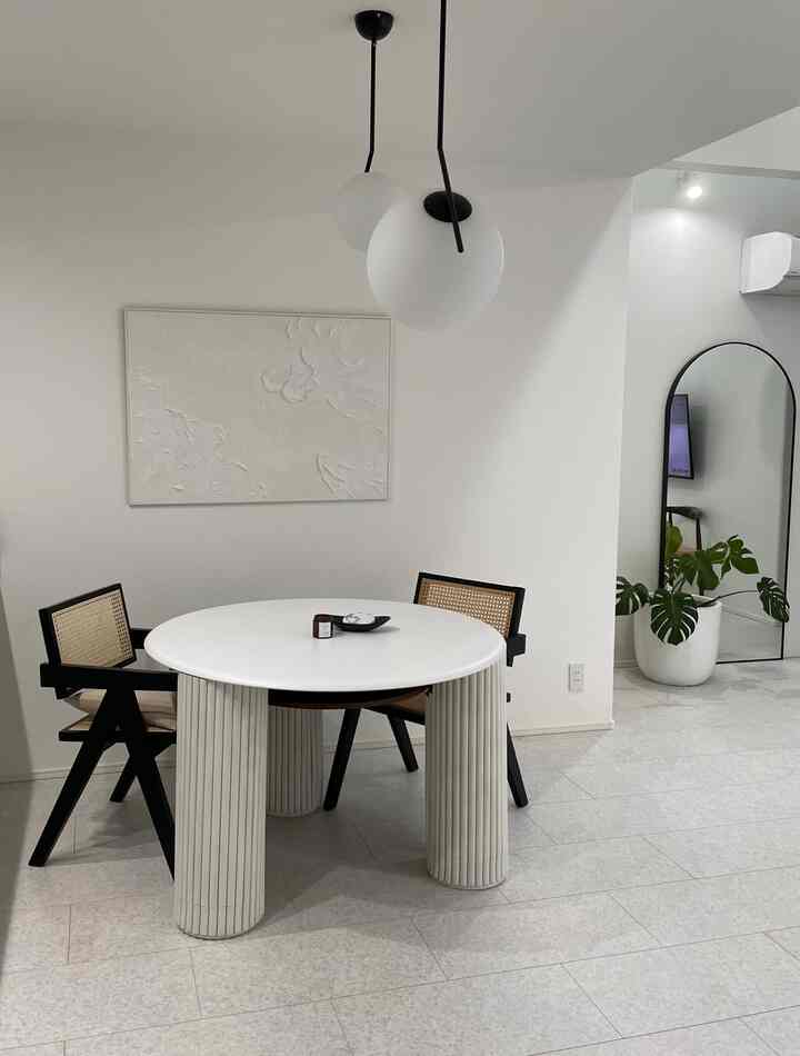 Simple modern living room in white and black tones, featuring a round table with rattan chairs in a clean space