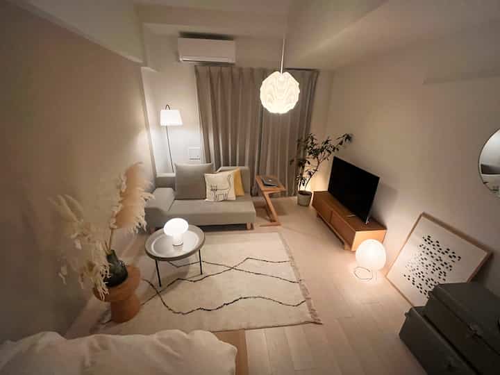 柔らかな白とライトブラウンの色調のリビング、シンプルでミニマルなソファと照明が印象的な雰囲気を作り出すインテリア