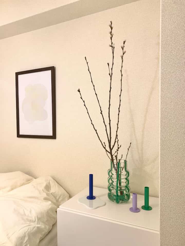 White and natural-toned bedroom featuring a Francfranc vase with branch decor placed on a clean dresser