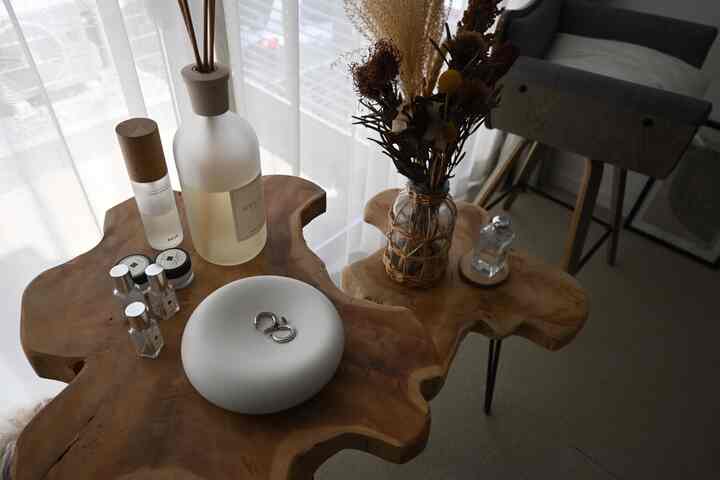 ナチュラルな木目調のサイドテーブルと白いカーテンが配置された雰囲気のある空間