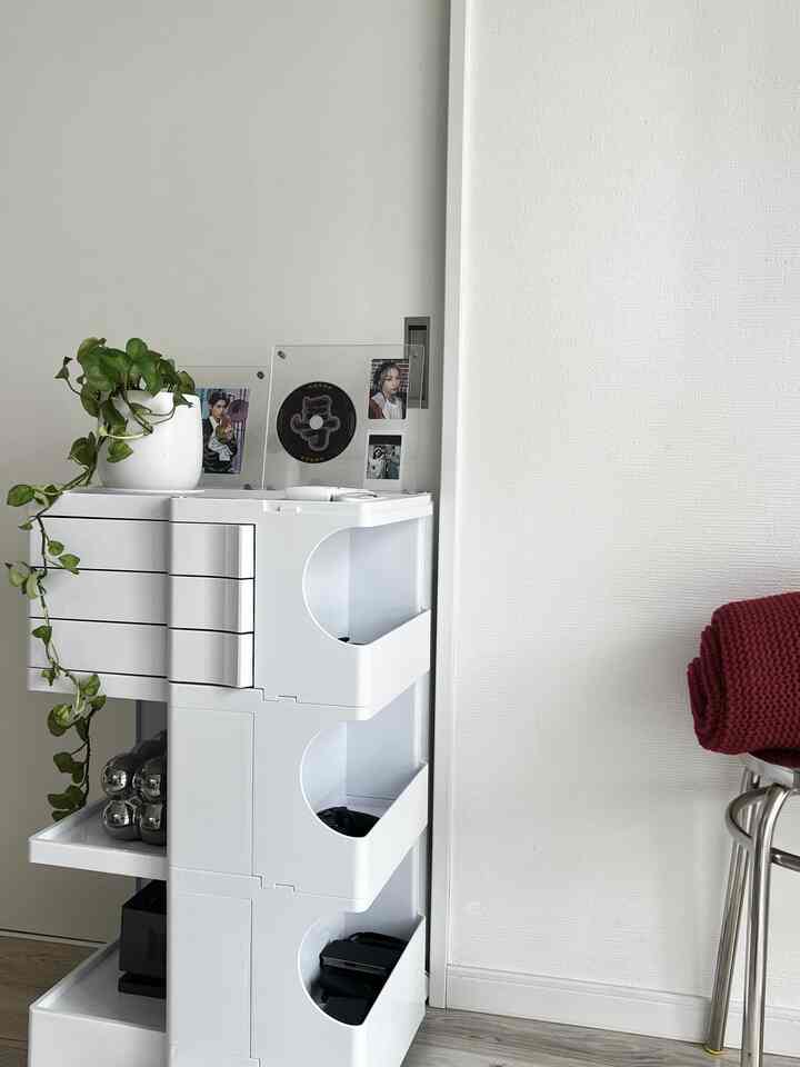 白を基調としたコンパクトな収納スペース、ステンレス製スツールと赤いスローがアクセントのモダンなインテリア