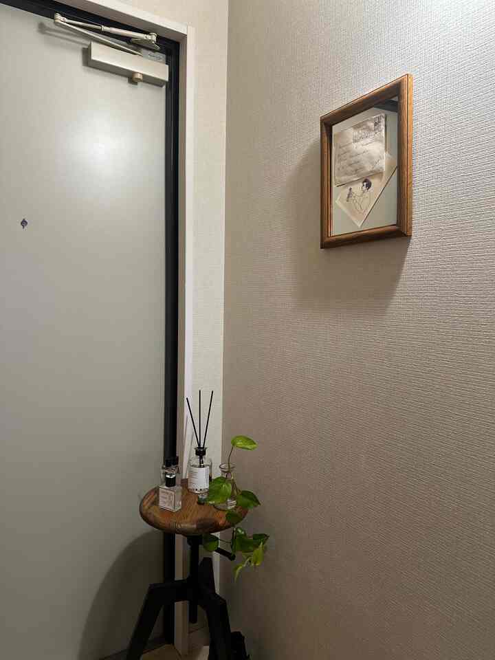 木目調とナチュラルカラーの玄関、ウッドスツールとディフューザーが配置された雰囲気のある空間