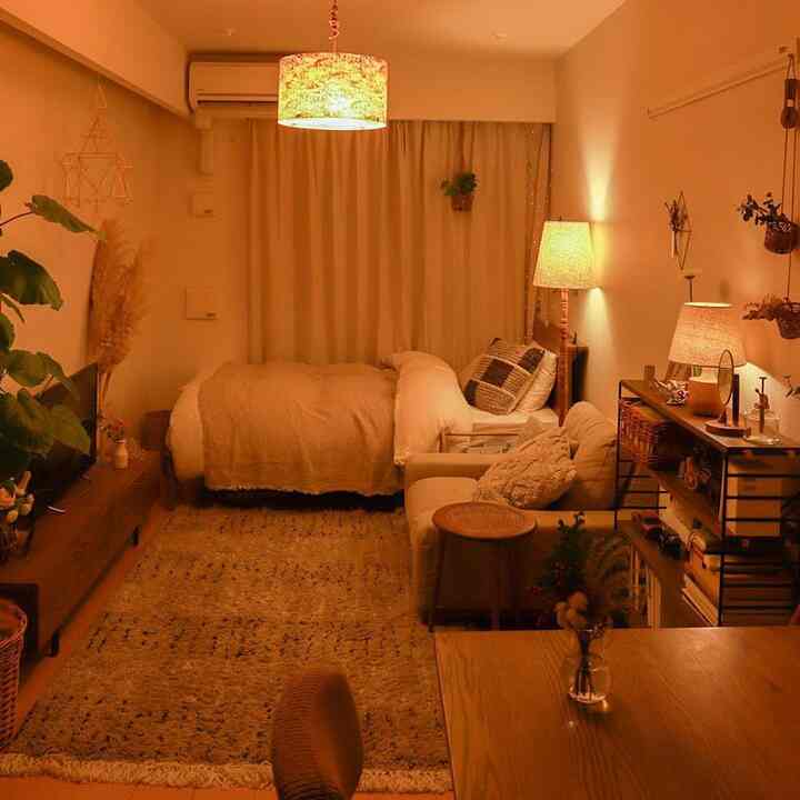 暖かいオレンジ色の照明が印象的なワンルーム、ソファとフロアランプ、ラグが配置された雰囲気のあるインテリア