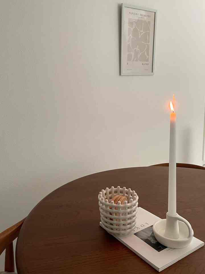 ナチュラルな木目調のダイニングテーブルと白い壁、灯されたキャンドルが配置されたシンプルなダイニング空間