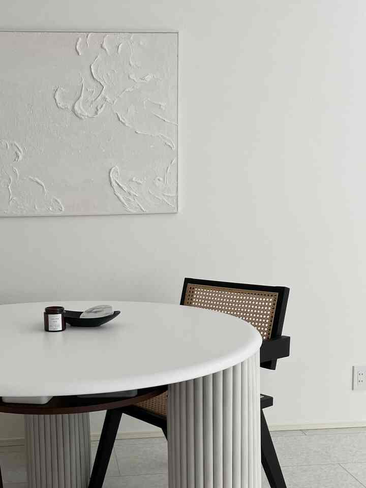 White-toned dining room featuring a round dining table and rattan chair with a minimal and natural atmosphere