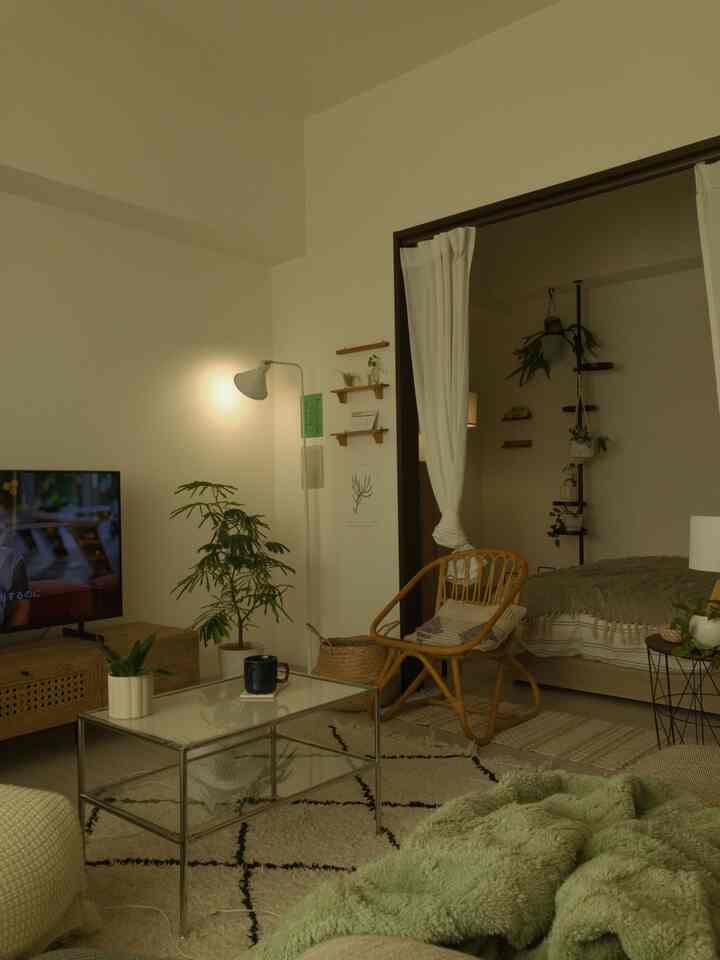 白い壁と自然な木目調家具の1LDKのリビングと寝室、中央にガラストップのコーヒーテーブルとラタンチェアが配置された落ち着いた空間